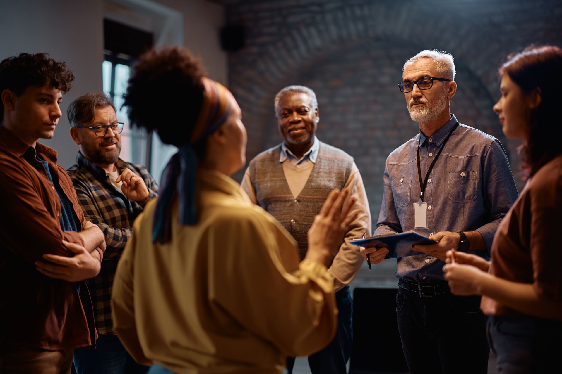 Mature psychotherapist having a counseling with group therapy attendees at mental health center.