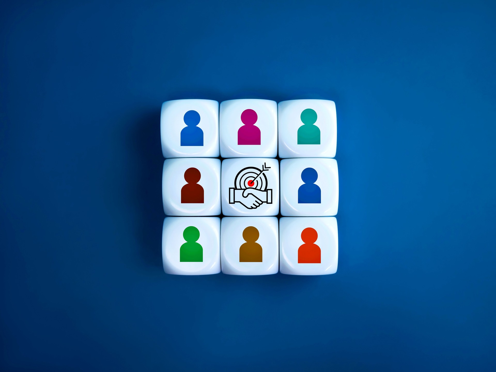 Stakeholder, business connection, teamwork, partnership and team building concept. Target with handshake deal icon surrounded with multicolor businessman symbol on white cube blocks stacked as one.